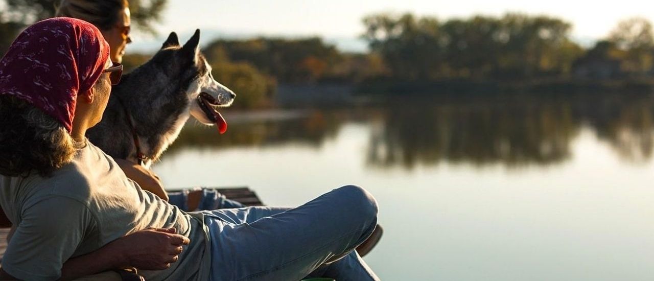 Woman and dog on dock overlooking river at Tributary