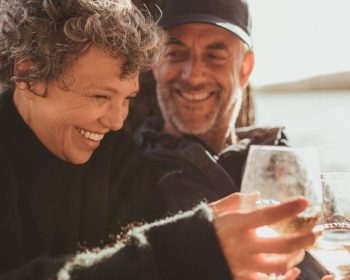 Couple with water glasses resting along riverbank