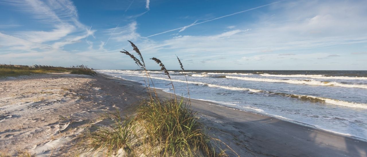 Waves rolling toward white sandy beach on clear day