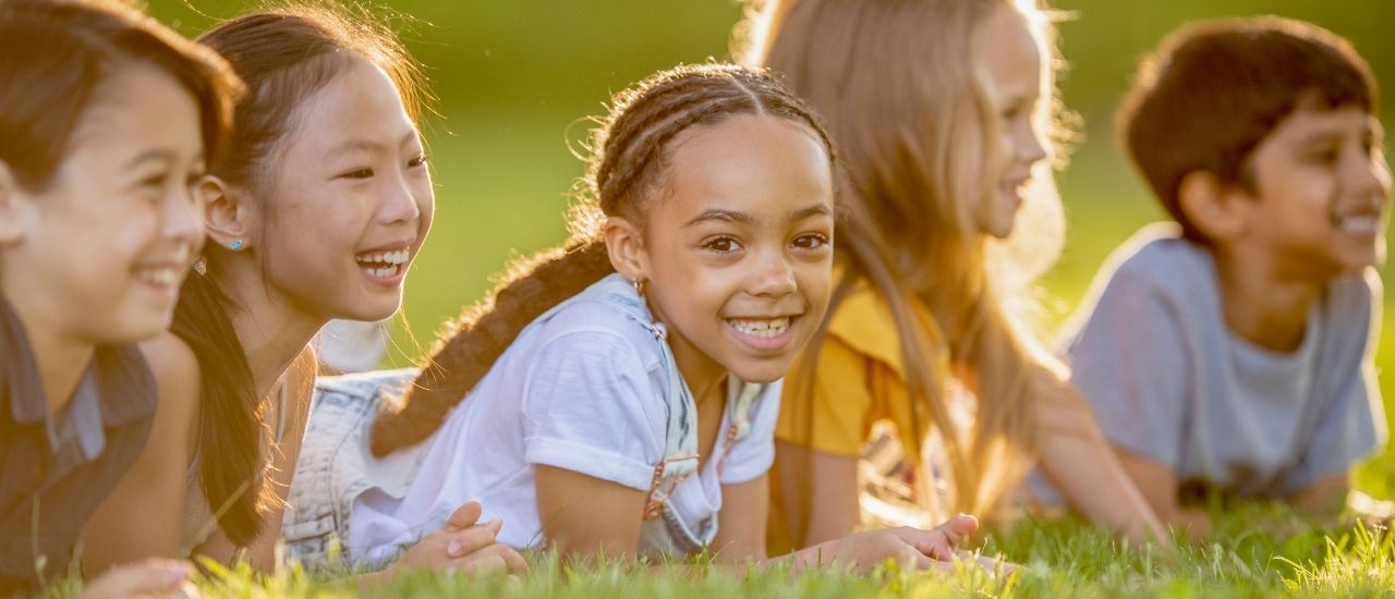 five kids laying in the grass at Tributary in the summertime
