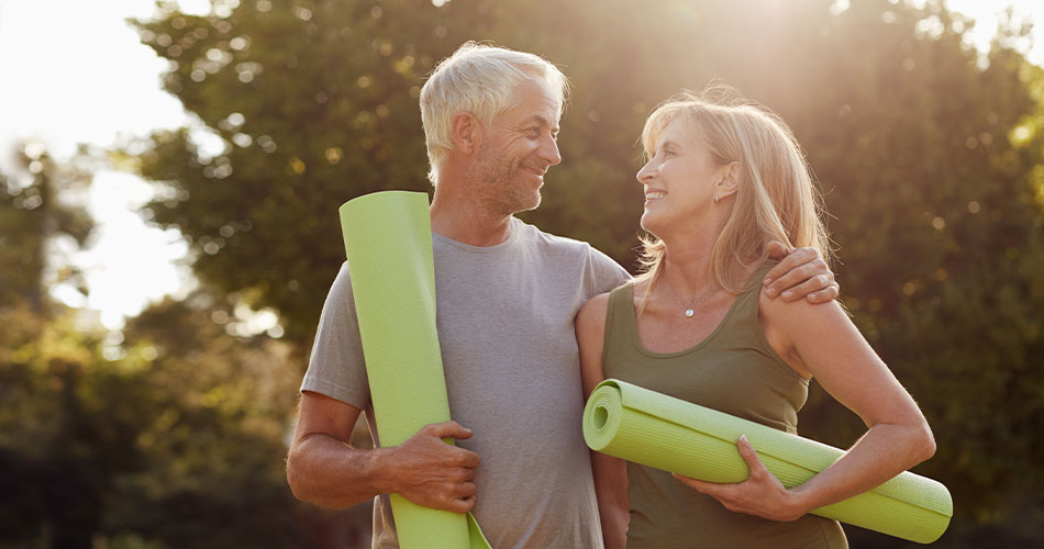retired couple holding yoga mats